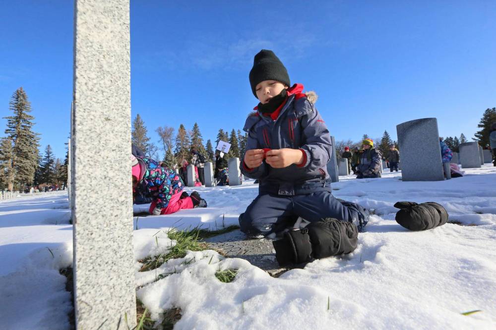 Grade 1 É;cole Harrison School student Jack Kellington prepares to place a poppy on the grave of a Canadian Forces soldier.