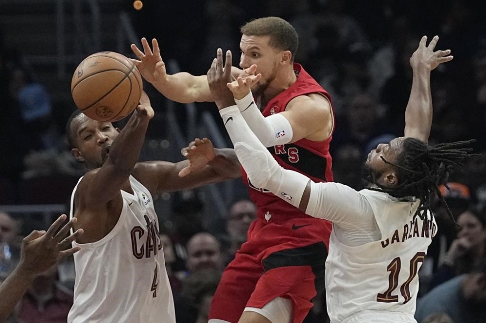 Toronto Raptors guard Malachi Flynn, centre, passes between Cleveland Cavaliers forward Evan Mobley and guard Darius Garland in the first half of an NBA basketball game, Sunday, Nov. 26, 2023, in Cleveland. THE CANADIAN PRESS/AP-Sue Ogrocki
