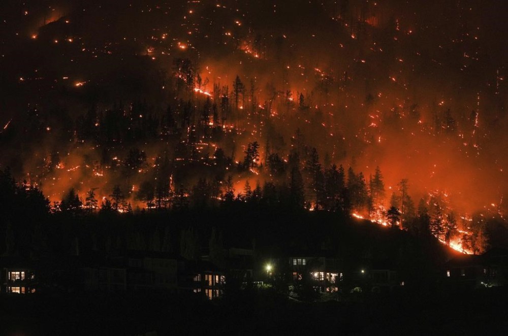 The McDougall Creek wildfire burns on the mountainside above houses in West Kelowna, British Columbia, on Aug. 18, 2023. Canada's first-ever climate adaptation strategy was little more than six weeks old when fast-moving wildfires swept through communities in British Columbia's southern Interior, forcing thousands to flee and destroying several hundred homes. THE CANADIAN PRESS/Darryl Dyck