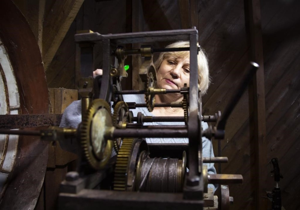 Expert Watchmaker, Liudmyla Pass, who recently arrived in Newfoundland and Labrador from the Ukraine makes an adjustment to the timing on the 1905 clock in the old Clock Tower of the old Post Office on Water Street in Carbonear, N.L., Friday, Dec. 22, 2023. THE CANADIAN PRESS/Paul Daly