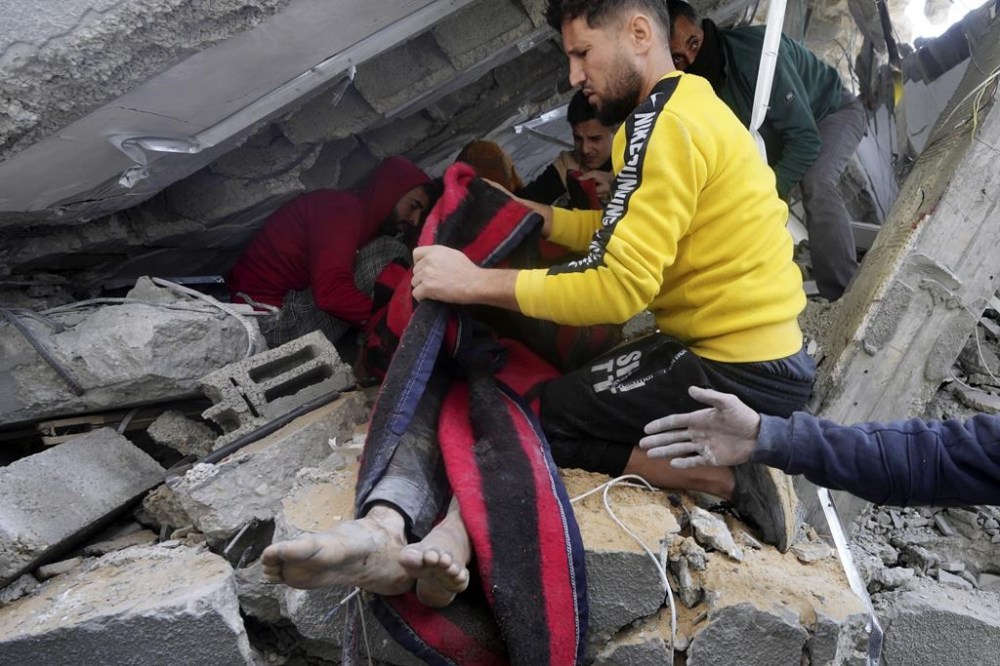 Palestinians pull a body out of the rubble of the Al Nawasrah family building destroyed in an Israeli airstrike in Maghazi refugee camp, central Gaza Strip, Monday, Dec. 25, 2023. (AP Photo/Adel Hana)