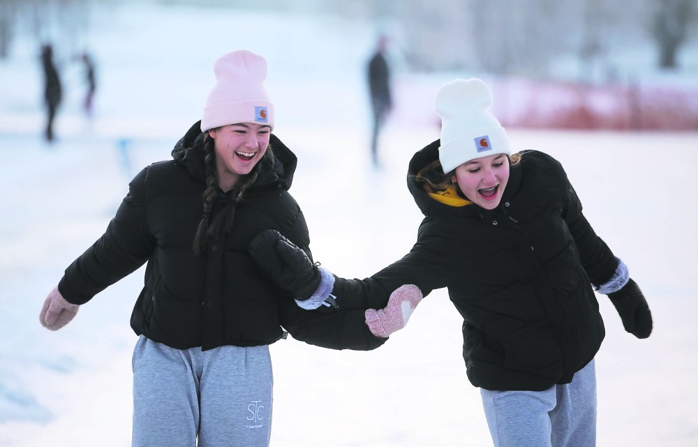 Friends Mya Lindenberg and Ella Vandaele laugh while skating at the oval in December. The city was forced to close the oval on Thursday due to warm weather making for poor ice conditions.