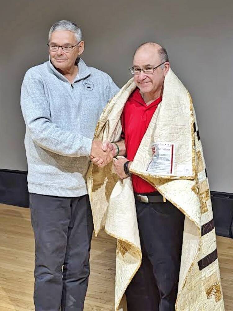 Bernie Verreault of the Quilts of Valour Canada Society wraps veteran Brett Mandryk with a comfort quilt, an award for service and commitment to the Canadian Armed Forces. (The Shilo Stag)