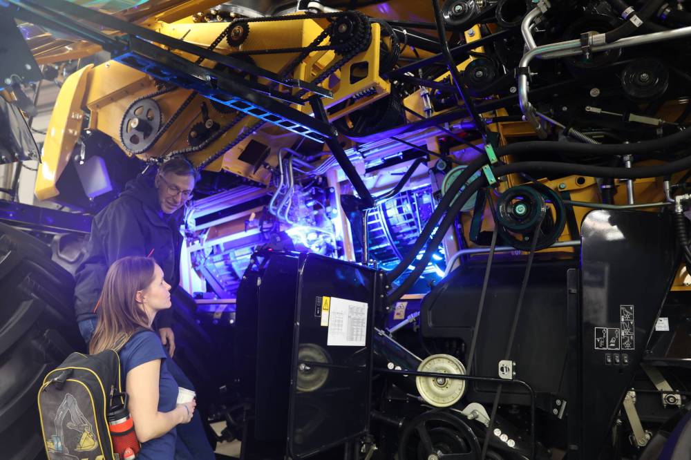 Bruce Miller points out some of the belts on the side panel of a New Holland combine to his daughter Sara Tufts at the Keystone Centre during Manitoba Ag Days, which wrapped up on Thursday. (Photos by Michele McDougall/The Brandon Sun)