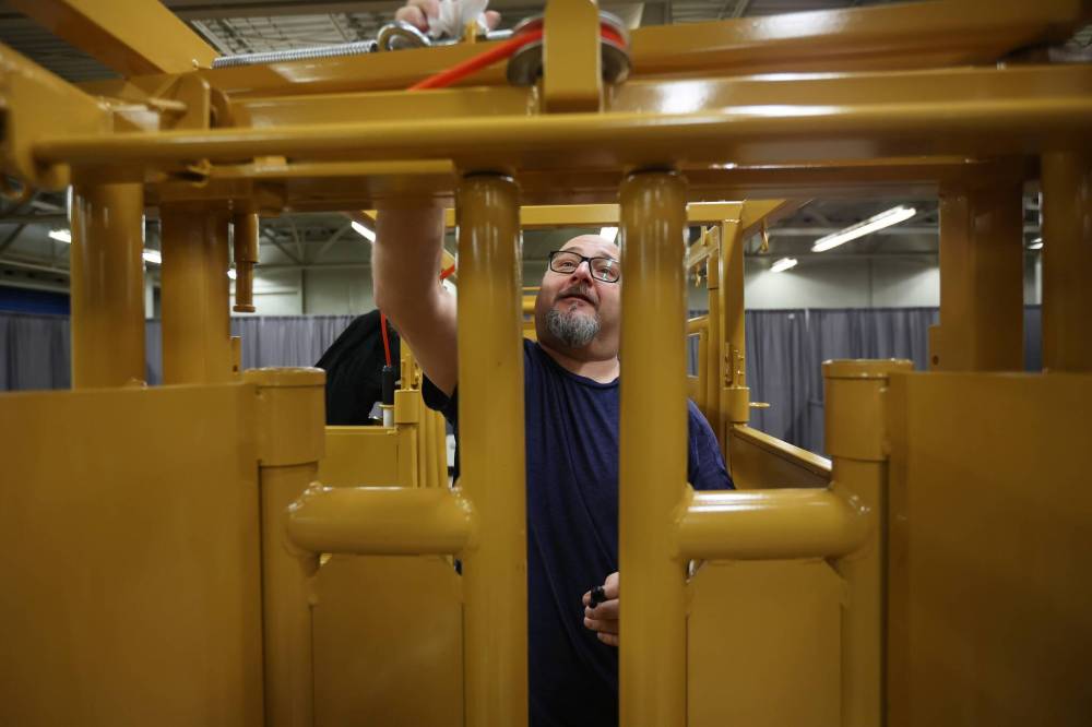 Gus Vigier with Tuff Livestock Equipment polishes a squeeze chute during setup for Manitoba Ag Days 2024 at the Keystone Centre on Monday.