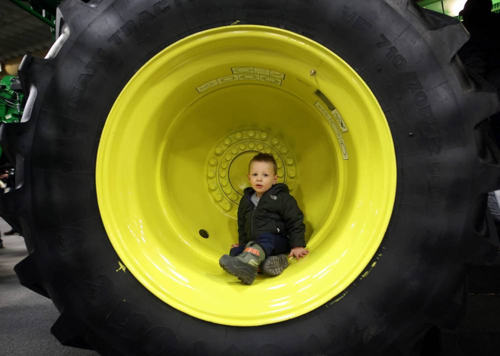 Two-year-old Austin Hird of Killarney explores the wheel well of a combine during Manitoba Ag Days 2024 at the Keystone Centre on Wednesday.
