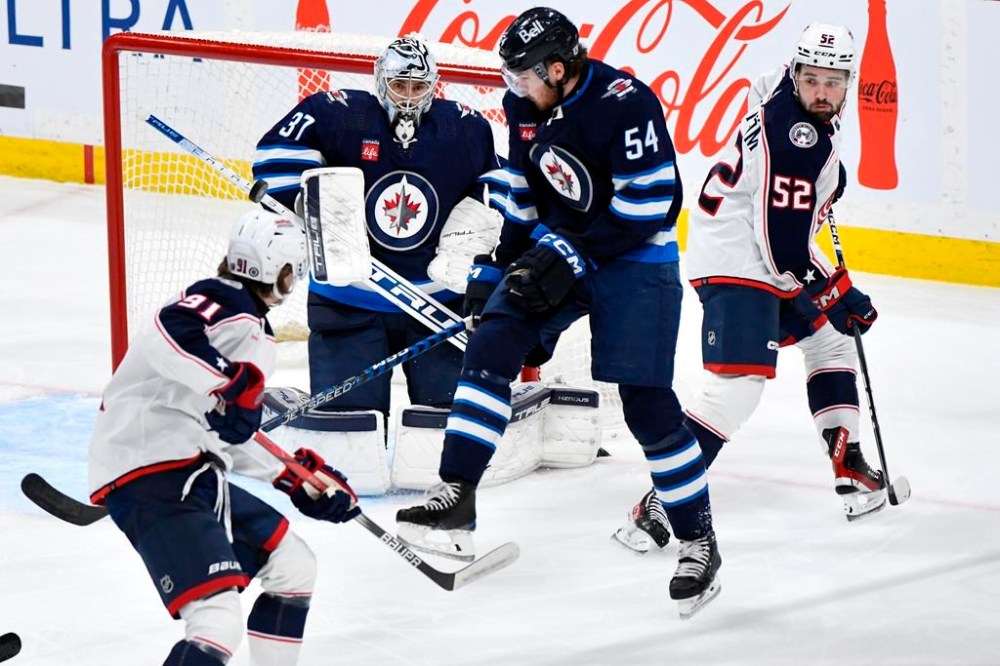 Winnipeg Jets' goaltender Connor Hellebuyck (37) makes a save on a shot by Columbus Blue Jackets' Kent Johnson (91) during the first period of NHL action in Winnipeg on Tuesday Jan. 9, 2024. THE CANADIAN PRESS/Fred Greenslade