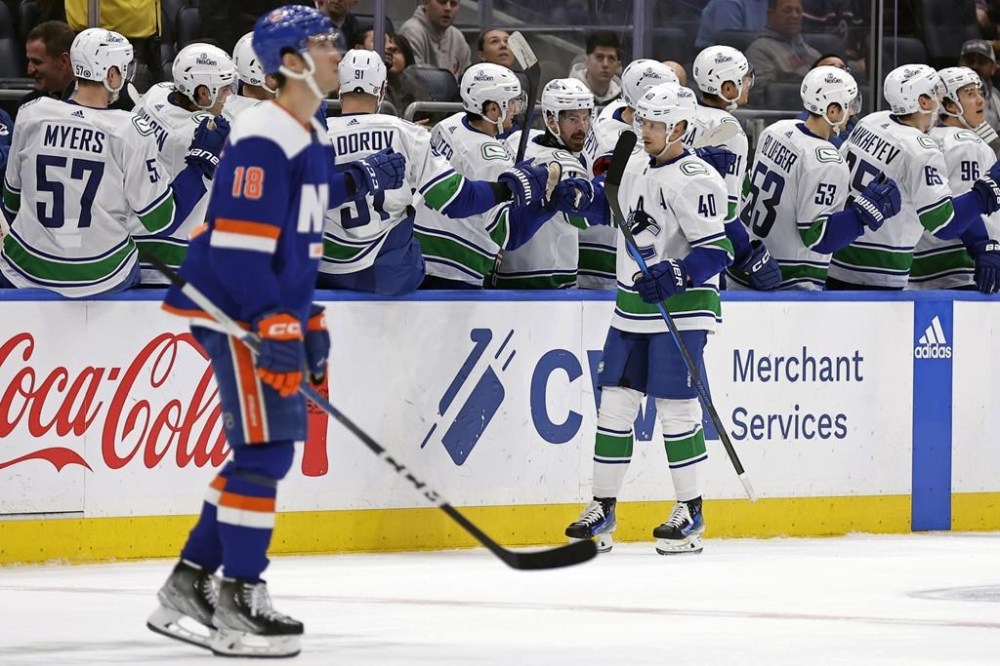 Vancouver Canucks center Elias Pettersson (40) celebrates with teammates after scoring a goal against the New York Islanders in the second period of an NHL hockey game Tuesday, Jan. 9, 2024, in Elmont, N.Y. (AP Photo/Adam Hunger)