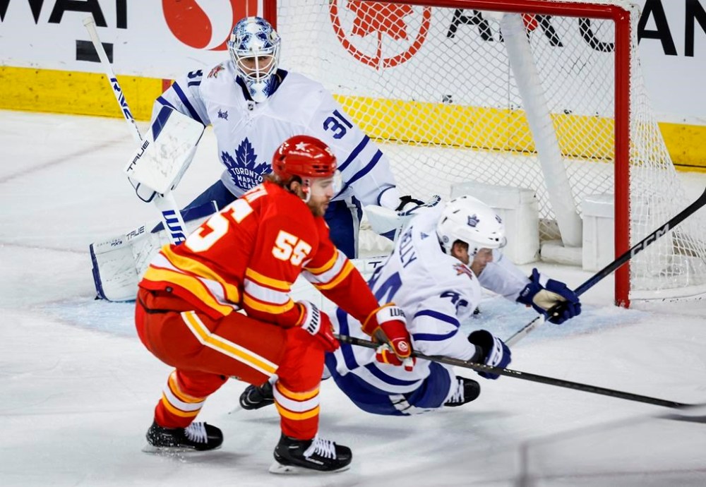 Toronto Maple Leafs goalie Martin Jones (31) looks on as Calgary Flames defenceman Noah Hanifin (55) trips defenceman Morgan Rielly (44) during second period NHL hockey action in Calgary, Thursday, Jan. 18, 2024. THE CANADIAN PRESS/Jeff McIntosh