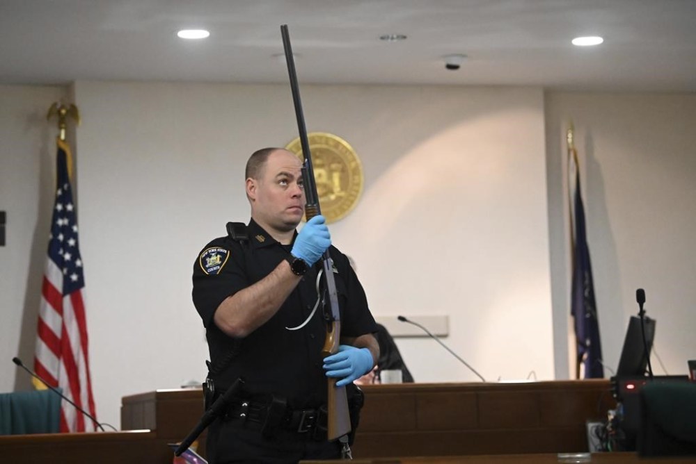 A NYS Court Police officer to holds Kevin Monahan's shotgun during summations in Monahan's murder trial, Tuesday, Jan. 23, 2024, at the Washington County Courthouse in Fort Edward, N.Y. Monahan, 66, is charged with second-degree murder in the death of Kaylin Gillis, who was riding in a caravan of two cars and a motorcycle that pulled into his dark, winding driveway in rural Hebron, about 40 miles (65 kilometers) north of Albany, near the Vermont border. (Will Waldron/The Albany Times Union via AP, Pool)