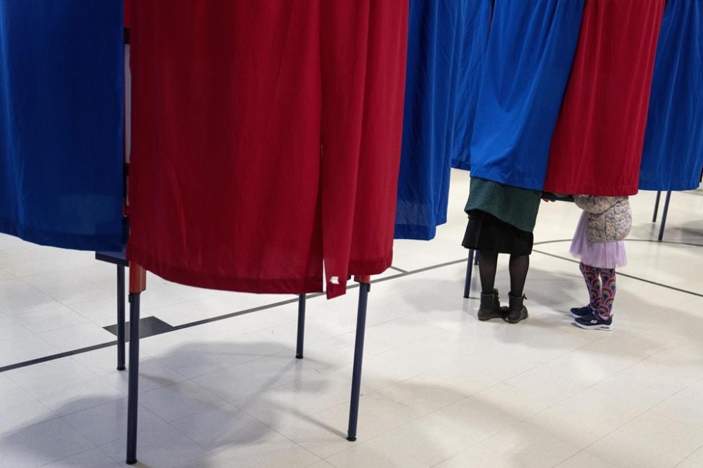 Kara Simard, left, votes with her daughter, Violet, 5, in the New Hampshire presidential primary at a polling site in Manchester, N.H., Tuesday, Jan. 23, 2024. (AP Photo/David Goldman)