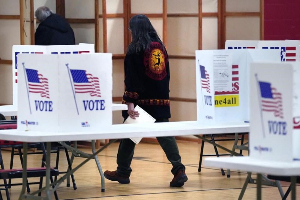 A resident, with ballot in hand, walks towards a voting booth at Auburn Village School, Tuesday, Jan. 23, 2024, in Auburn, N.H., as New Hampshire's famously independent-minded electorate makes its pick for the 2024 presidential nominees. (AP Photo/Charles Krupa)