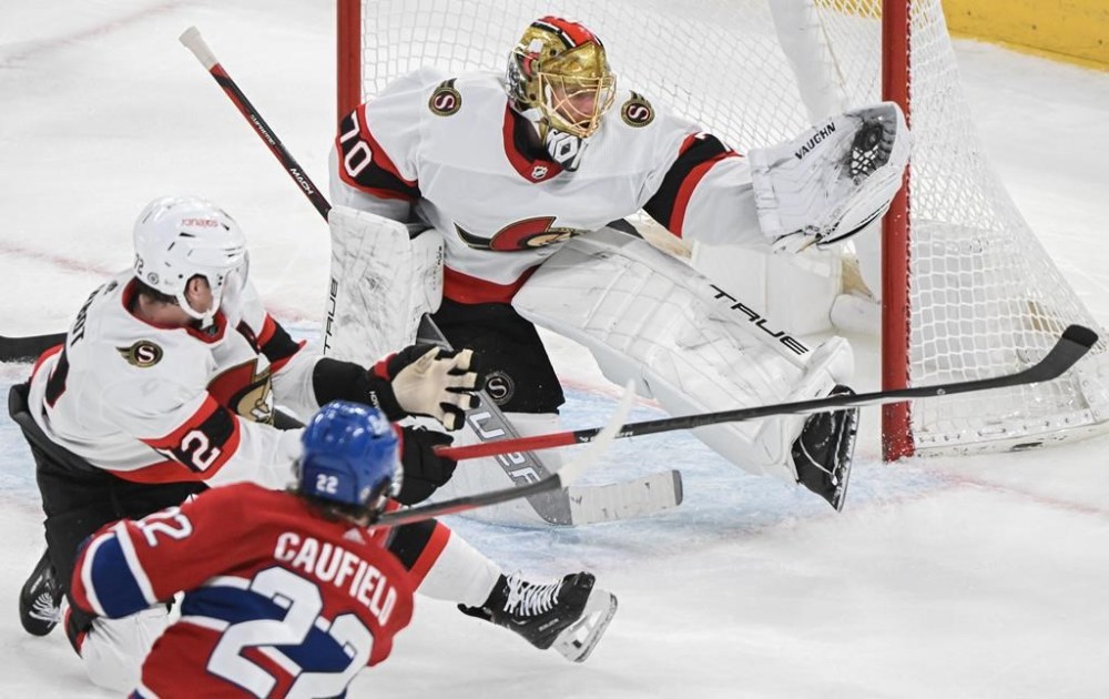 Ottawa Senators goaltender Joonas Korpisalo makes a glove save on Montreal Canadiens' Cole Caufield (22) as Senators' Thomas Chabot (72) tries to block the shot during second period NHL hockey action in Montreal, Tuesday, Jan. 23, 2024. THE CANADIAN PRESS/Graham Hughes