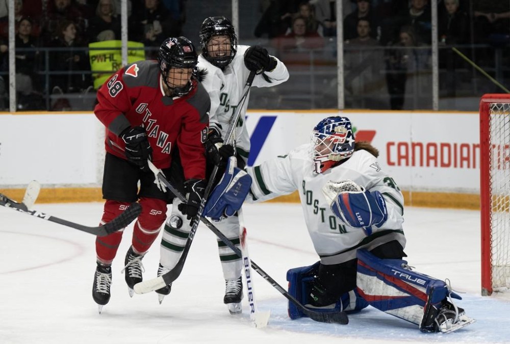 Boston's Sidney Morin, centre, grimaces as she blocks a shot with her knee while battling Ottawa's Lexie Adzija in front of Boston goalie Aerin Frankel during second period PWHL action, Wednesday, January 24, 2024 in Ottawa. THE CANADIAN PRESS/Adrian Wyld