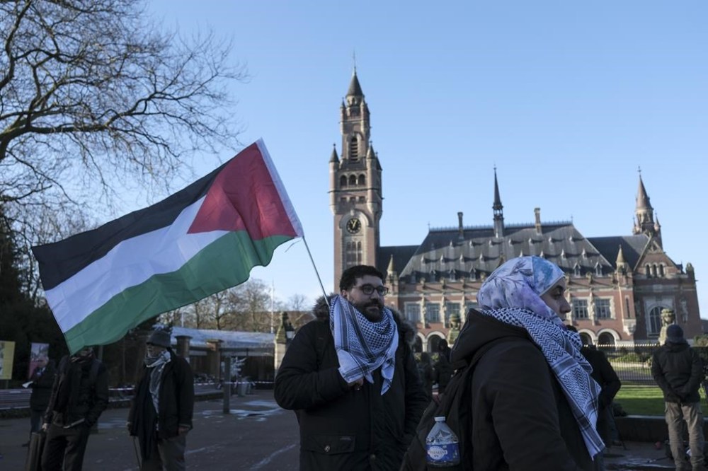 Protesters and media gather outside the Peace Palace, which houses the International Court of Justice, or World Court, in The Hague, Netherlands, Friday, Jan. 26, 2024. Israel is set to hear whether the United Nations' top court will order it to end its military offensive in Gaza during a case filed by South Africa accusing Israel of genocide. (AP Photo/Patrick Post)
