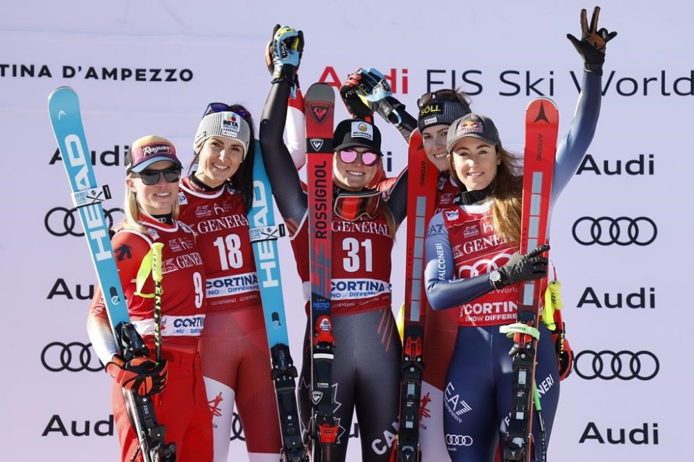 Austria's Stephanie Venier, second from left, winner of an alpine ski, women's World Cup downhill race, celebrates on the podium with second-placed Switzerland's Lara Gut Behrami, left, and Canada's Valerie Grenier, third from right, Austria's Christina Ager, second from right, and Italy's Sofia Goggia, right, who tied for third place, in Cortina d'Ampezzo, Italy, Friday, Jan. 26, 2024. (AP Photo/Alessandro Trovati)