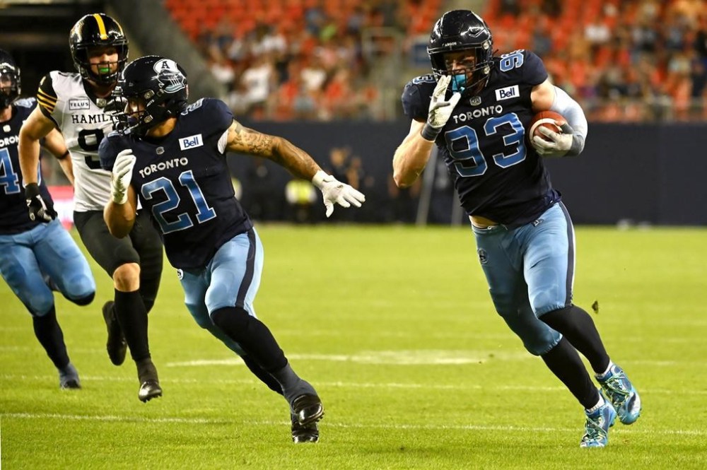 Toronto Argonauts defensive lineman Benoit Marion (93) runs a recovered blocked punt attempt by the Hamilton Tiger-Cats for a touchdown during second half CFL football action in Toronto on Saturday, August 6, 2022. The Argonauts signed linebacker Jack Cassar and Marion to contract extensions Tuesday. THE CANADIAN PRESS/Jon Blacker