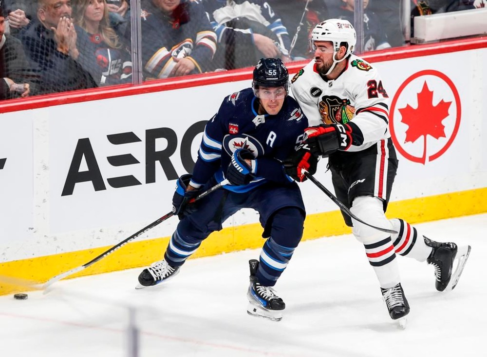 Winnipeg Jets' Mark Scheifele (55) and Chicago Blackhawks' Jaycob Megna (24) go for the loose puck during first period NHL action in Winnipeg on Thursday, January 11, 2024. The Jets activated Scheifele from injured reserve hours before their game Tuesday night at Pittsburgh. THE CANADIAN PRESS/John Woods