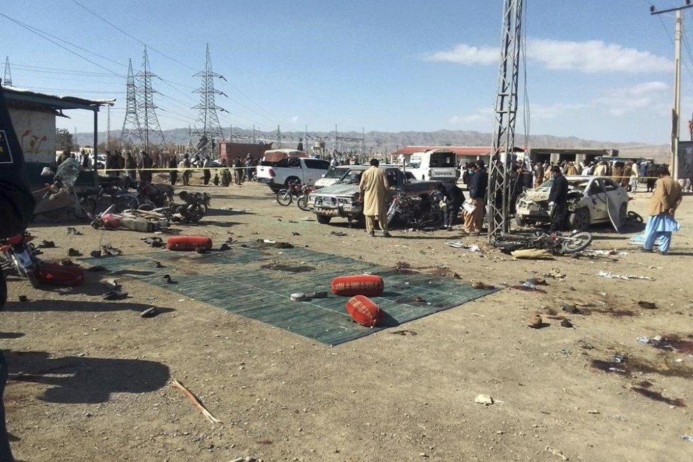 Security officials examine the scene of a bomb blast in Khanozai, Pashin, a district of Pakistan's Baluchistan province, Wednesday, Feb. 7, 2024. A pair of bombings at the election offices of a political party and an independent candidate in southwest Pakistan killed some people and wounded more, officials said Wednesday, the day before parliamentary elections are to be held. (AP Photo/Shah Hussain)