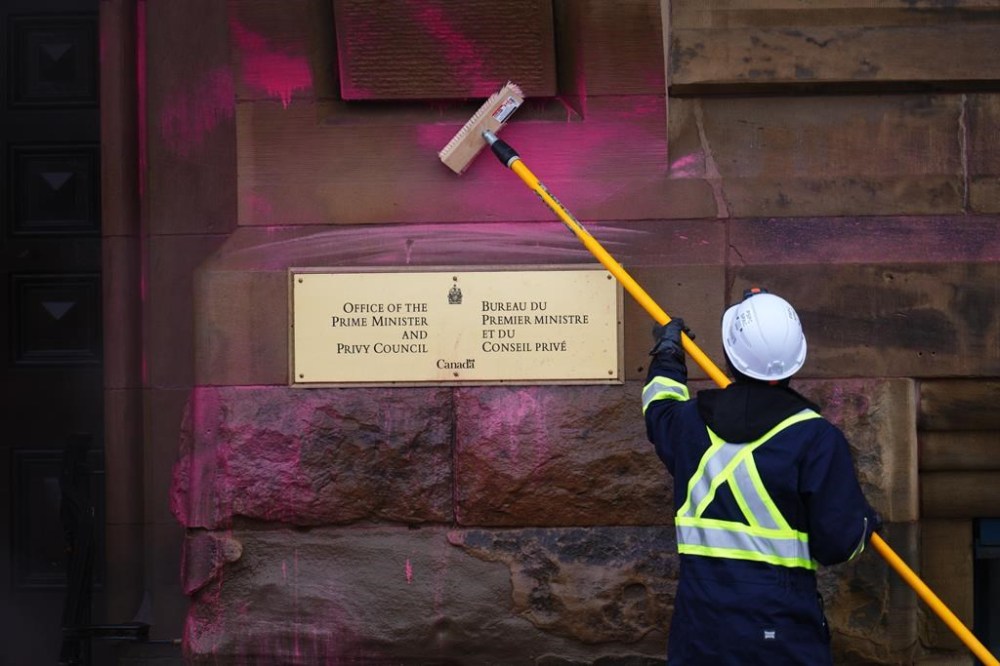 A worker removes pink paint from the exterior of the entrance to the prime minister's office on Wellington Street in Ottawa on Wednesday, Feb.7, 2024. Five people are facing mischief charges after the Prime Minister's Office Building in Ottawa was doused with pink paint and downtown traffic disrupted by climate protesters this morning.THE CANADIAN PRESS/Sean Kilpatrick