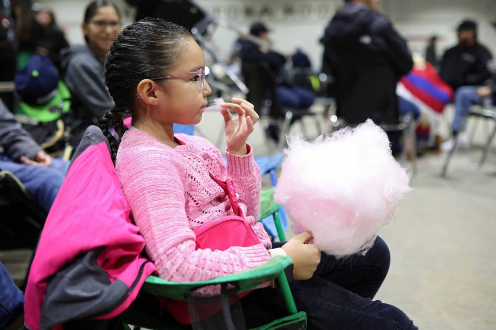 Six-year-old Lili Kaysaywaysemat enjoys some cotton candy while waiting for the Powwow Grand Entry to start.