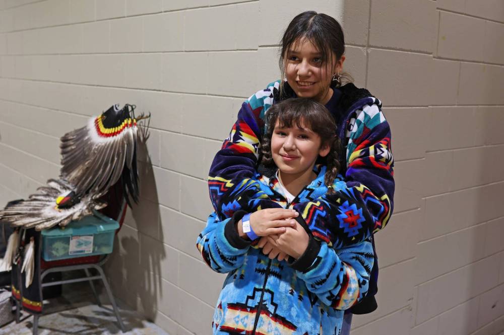 Nikki Wanbdiska of Sioux Valley Dakota Nation embraces her younger sister Mila prior to the Powwow Grand Entry.