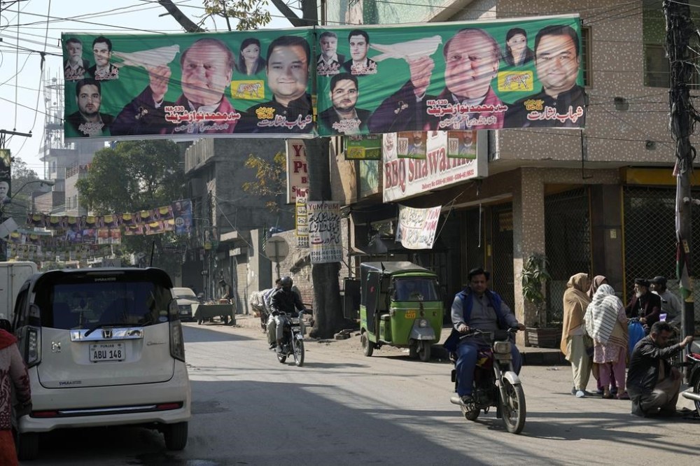 A motorcyclist rides on a road covered with election campaign posters from political parties, in Lahore, Pakistan, Friday, Feb. 9, 2024. The results of Pakistan's elections were delayed a day after the vote that was marred by sporadic violence, a mobile phone service shutdown and the sidelining of former Prime Minister Imran Khan and his party. (AP Photo/K.M. Chaudary)