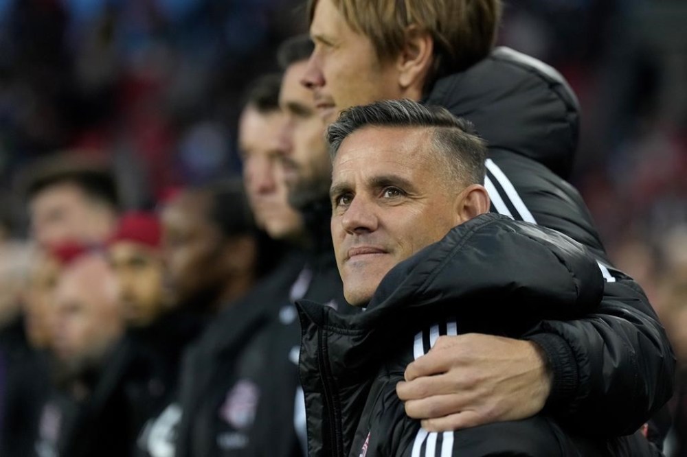 Toronto FC's incoming head coach John Herdman is embraced as they sing the national anthem prior to first half MLS soccer action against the Orlando City, in Toronto on Saturday, Oct. 21, 2023. Toronto FC has opened the second phase of its training camp, this time in California with three friendlies in the next week. THE CANADIAN PRESS/Nathan Denette