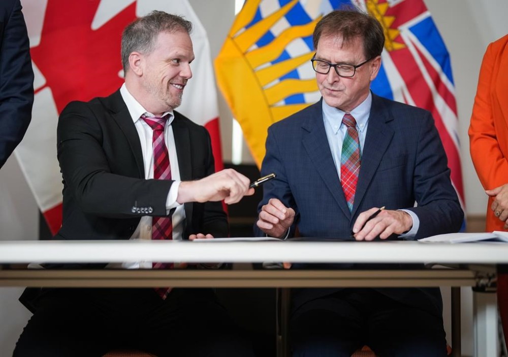 Federal Health Minister Mark Holland, left, and B.C. Health Minister Adrian Dix sign a document after a health care funding announcement, in Vancouver, B.C., Monday, Feb. 12, 2024. British Columbia and Ottawa have announced $733 million in new federal funding over the next five years to improve health care for the province’s seniors. THE CANADIAN PRESS/Darryl Dyck