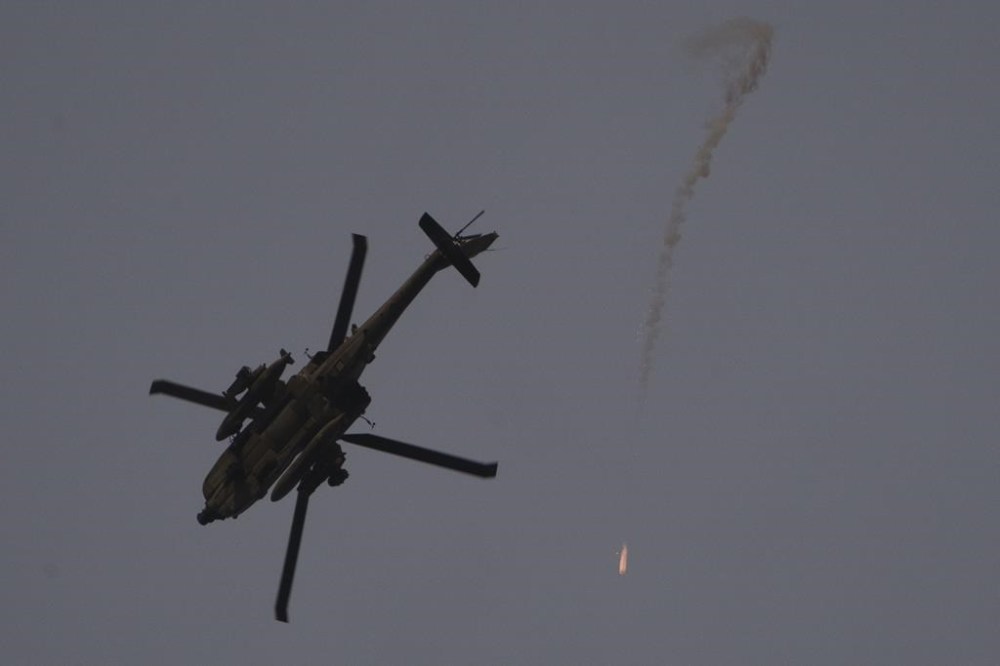 An Israeli helicopter releases flares as it flies over Israeli-Gaza border, as seen from southern Israel, Monday, Feb. 12, 2024. American and Canadian officials say they are still trying to sort out what caused the Israeli military to take citizens from their home in the Gaza Strip.THE CANADIAN PRESS/AP-Leo Correa