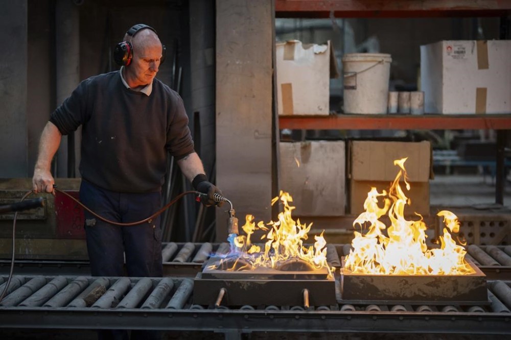 Sand moulds are burnt with a blowtorch by a foundry man as part of the process to create BAFTA masks at FSE Foundry in Braintree, Essex on Wednesday, Jan. 24, 2024. (Scott A Garfitt/Invision/AP)