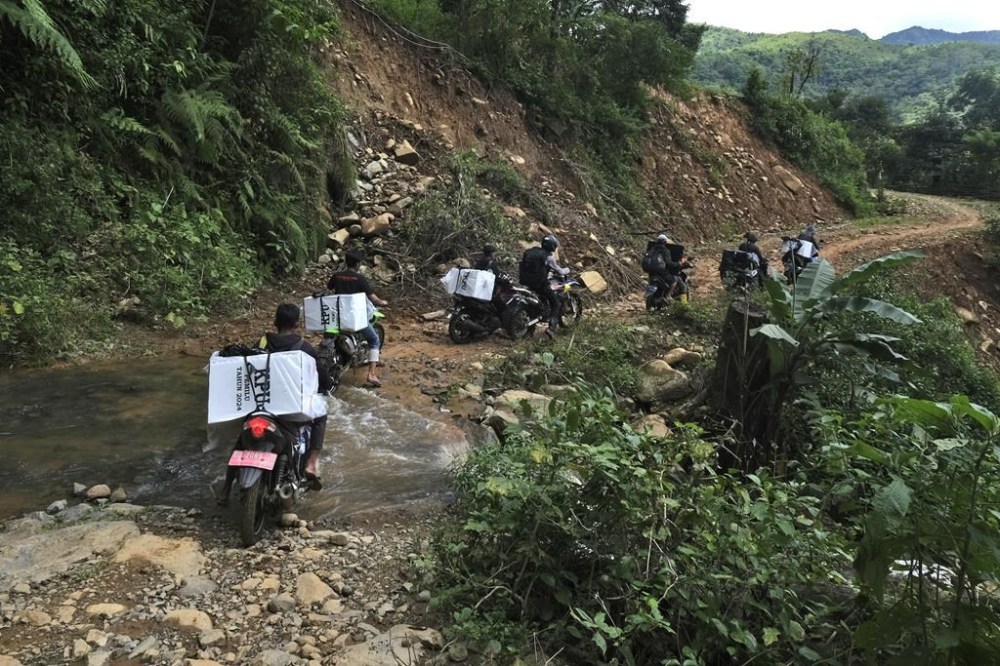 Electoral workers carry ballot boxes and other election paraphernalia on motorbikes to distribute them to polling stations in remote villages ahead of the Feb. 14 election in Maros, Indonesia, Tuesday, Feb. 13, 2024. Indonesia, the world's third-largest democracy, will open its polls on Wednesday to nearly 205 million eligible voters in presidential and legislative elections, the fifth since Southeast Asia's largest economy began democratic reforms in 1998. (AP Photo/Masyudi S. Firmansyah)