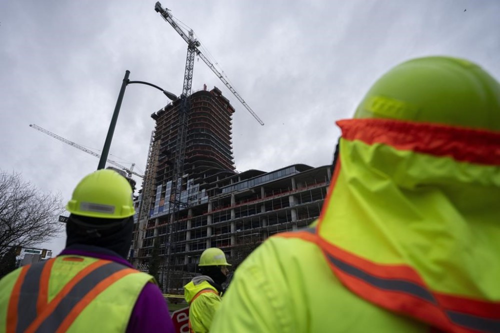 Construction workers gather outside of the Oakridge Mall site after a load on a crane fell off smashing multiple floors of the building in Vancouver, B.C. on Wednesday, Feb. 21, 2024. THE CANADIAN PRESS/Ethan Cairns