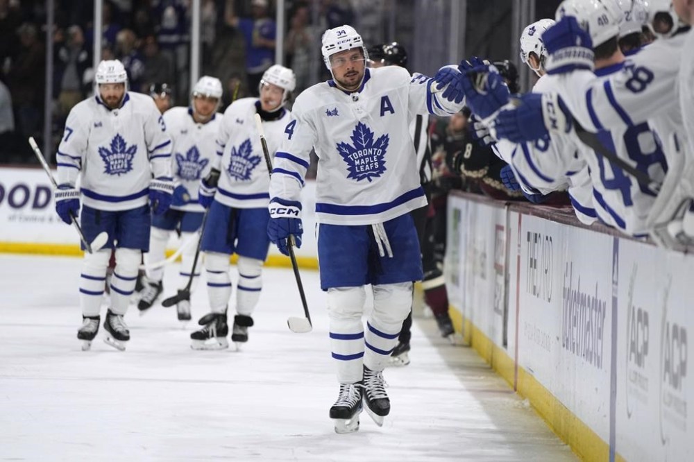 Toronto Maple Leafs centre Auston Matthews (34) is congratulated after scoring his 50th goal of the season, against the Arizona Coyotes during the first period of an NHL hockey game Wednesday, Feb. 21, 2024, in Tempe, Ariz. (AP Photo/Rick Scuteri)