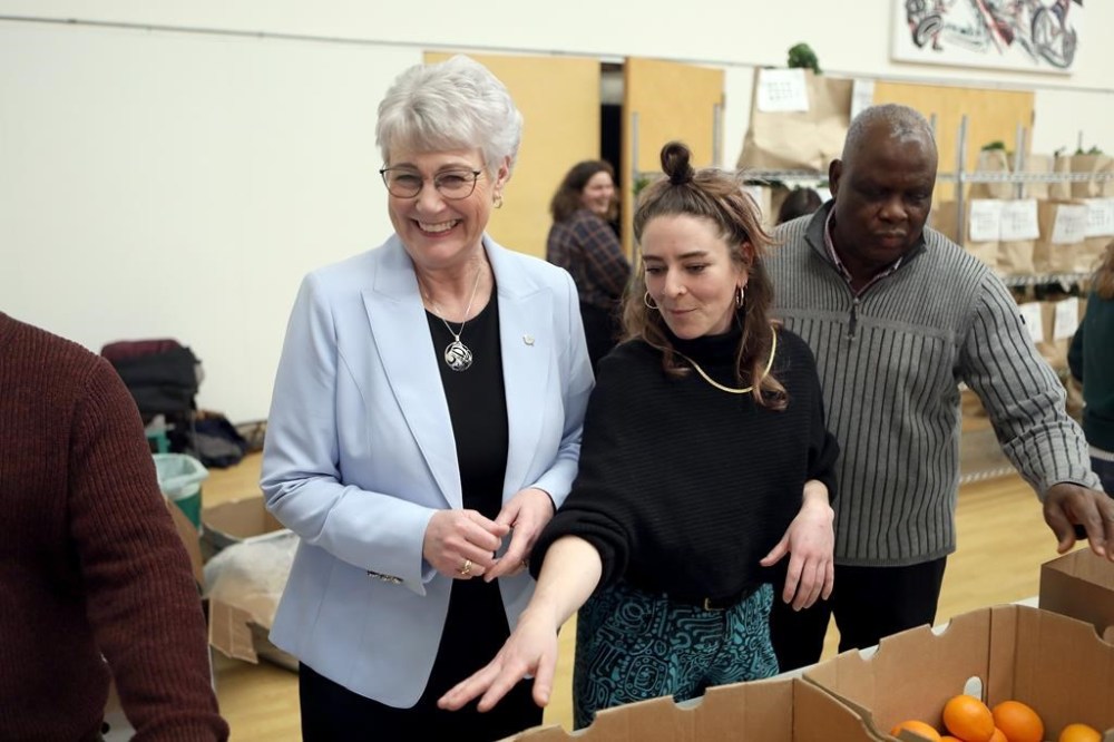 Finance Minister Katrine Conroy, left, is joined by food security co-ordinator Jesse Wallis and volunteer Vincent Aigbefo as they pack groceries for a subscription based program made up of volunteers called Good Food Box during a photo opportunity at the Fernwood Community Centre in Victoria, Wednesday, Feb. 21, 2024. THE CANADIAN PRESS/Chad Hipolito