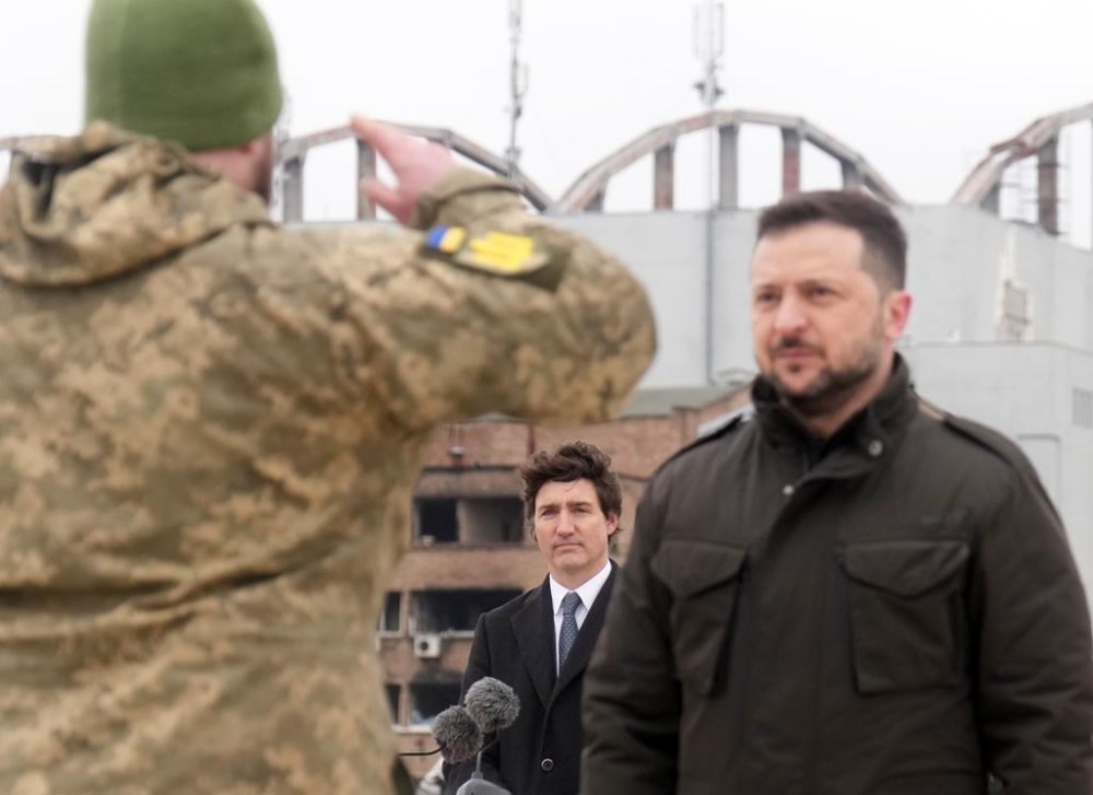 Prime Minister Justin Trudeau watches as Ukrainian President Volodymyr Zelenskyy is saluted by soldiers during a ceremony at Hostomel Airport in Kyiv on Saturday, February 24, 2024. The ceremony was part of a day of commemorations to mark the second anniversary of the start of the war in Ukraine. THE CANADIAN PRESS/Nathan Denette