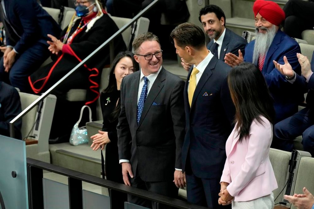 Michael Spavor (left) and Michael Kovrig share a moment during a standing ovation in the House of Commons in Ottawa, Friday, March 24, 2023. Spavor has reached a settlement with the federal government over his three-year detention in China. THE CANADIAN PRESS/Adrian Wyld