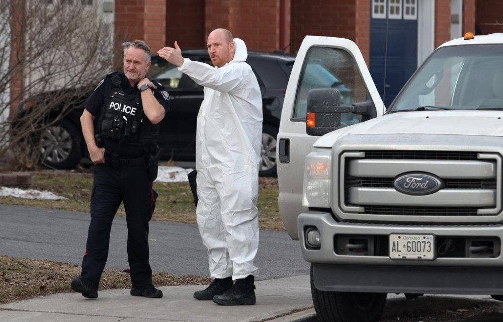 A police officer and a member of the coroner's office talk at the scene of a homicide where six people were found dead in the Barrhaven suburb of Ottawa on Thursday, March 7, 2024. THE CANADIAN PRESS/ Patrick Doyle
