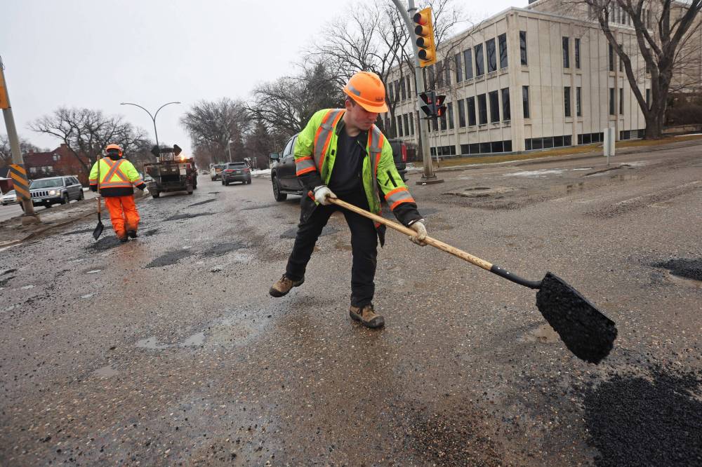 Nathaniel Hegg with Manitoba Transportation and Infrastructure fills potholes at the intersection of 18th Street and Victoria Avenue recently. Eighteenth Street still isn't in great shape and it can't wait a year for repair. (File)