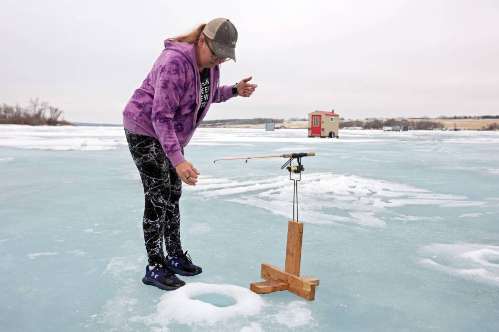 Brenda Hopkie checks one of her fishing lines at her ice fishing shack on the Rivers Reservoir.