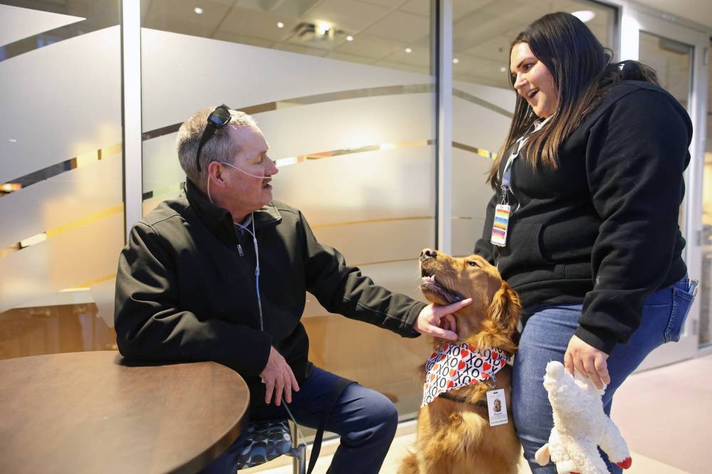 Stephanie Hofer (right) and her dog Waylon with Prairie Area Therapy Dogs (PATDogs) visit with Steven Logan in the atrium at the Brandon hospital on Wednesday evening.