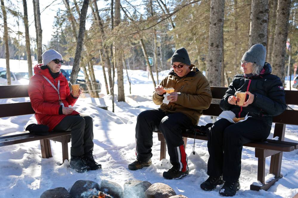 Visitors to the Friends of Riding Mountain National Park learning centre on Saturday enjoy cups of pea soup by a fire. (Colin Slark/The Brandon Sun)