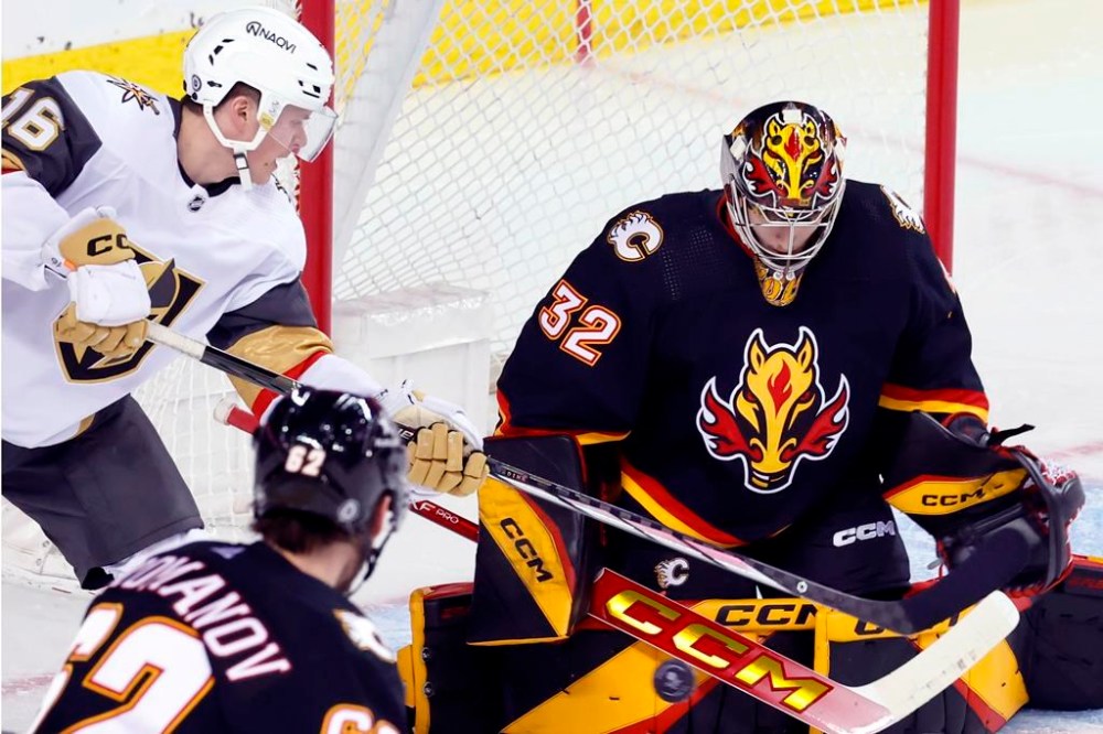 Vegas Golden Knights' Pavel Dorofeyev, left, has a shot stopped by Calgary Flames goalie Dustin Wolf during second period NHL hockey action in Calgary, Thursday, March 14, 2024. THE CANADIAN PRESS/Larry MacDougal