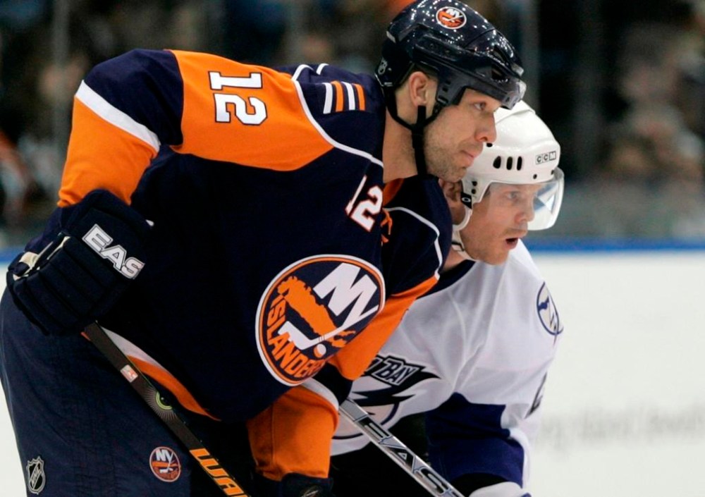 Chris Simon, once one of the hockey's most feared enforcers, has died. He was 52. Simon (12) and Tampa Bay Lightning's Craig MacDonald watch a faceoff during the third period of an NHL hockey game on Feb. 21, 2008, in Uniondale, N.Y. THE CANADIAN PRESS/AP-Frank Franklin II