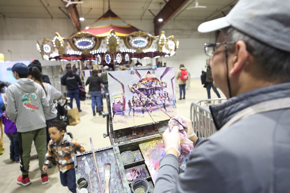 Well-known Brandon painter Weiming Zhao puts the final touches on a portrait of the merry-go-round in the Manitoba Room during the first day of the Royal Manitoba Winter Fair on Monday afternoon. (Matt Goerzen/The Brandon Sun)