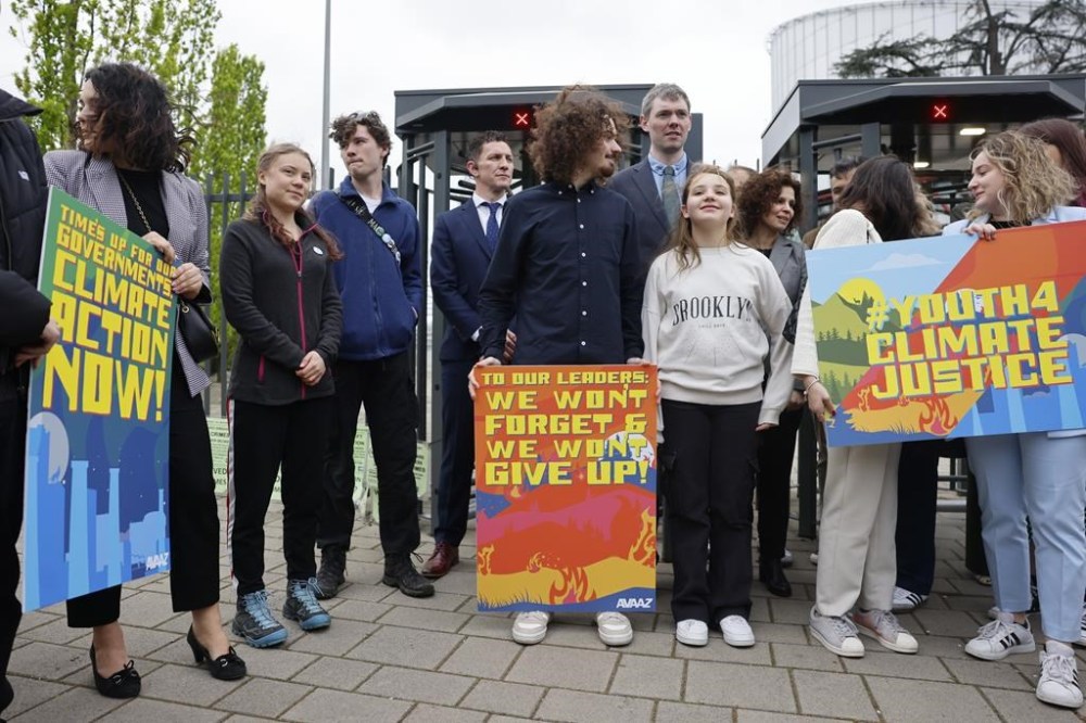 Swedish climate activist Greta Thunberg, second left, joins youths from Portugal during a demonstration outside the European Court of Human Rights Tuesday, April 9, 2024 in Strasbourg, eastern France. Europe's highest human rights court will rule Tuesday on a group of landmark climate change cases aimed at forcing countries to meet international obligations to reduce greenhouse gas emissions. The European Court of Human Rights will hand down decisions in a trio of cases brought by a French mayor, six Portuguese youngsters and more than 2,000 elderly Swiss women who say their governments are not doing enough to combat climate change. (AP Photo/Jean-Francois Badias)