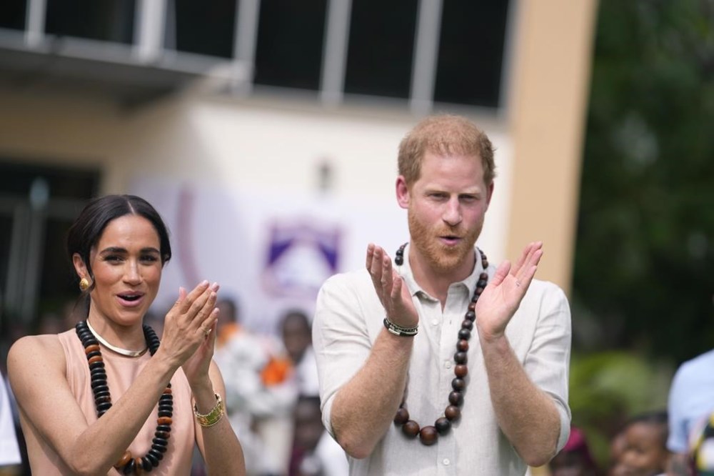 Prince Harry and Meghan gesture as they visit children at the Lights Academy in Abuja, Nigeria, Friday, May 10, 2024. Prince Harry and his wife Meghan have arrived in Nigeria to champion the Invictus Games, which he founded to aid the rehabilitation of wounded and sick servicemembers and veterans. (AP Photo/Sunday Alamba)