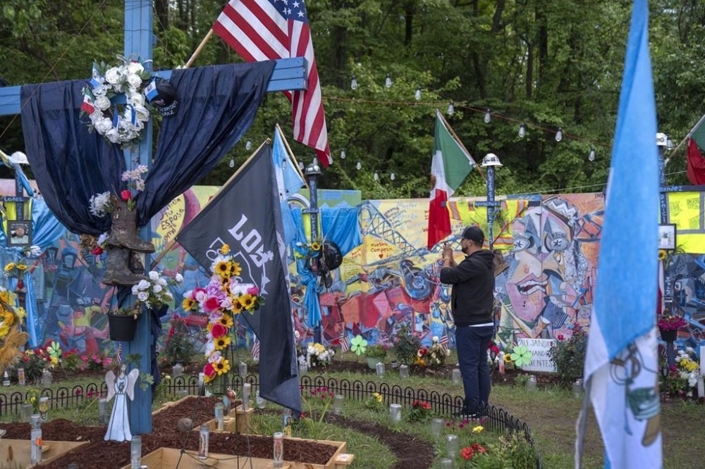A visitor walks through a memorial along a road leading to a park at the base of the collapsed Francis Scott Key Bridge, Sunday, May 12, 2024, in Baltimore. An effort to remove sections of the collapsed bridge resting on the container ship Dali was postponed on Sunday. (AP Photo/Mark Schiefelbein)
