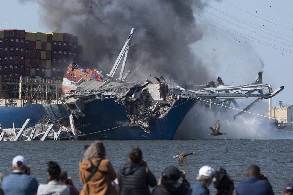 Explosive charges are detonated to bring down sections of the collapsed Francis Scott Key Bridge resting on the container ship Dali on Monday, May 13, 2024, in Baltimore. (AP Photo/Mark Schiefelbein)