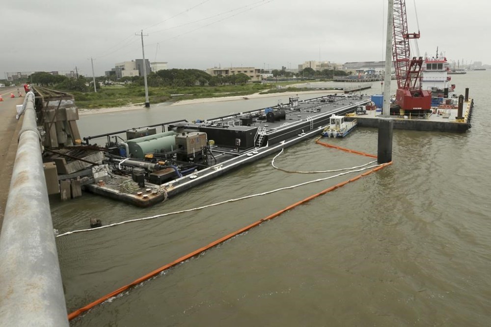Spill booms surround a barge at the Pelican Island bridge in Galveston, Texas, Wednesday, May 16, 2024. The barge collided with the bridge Tuesday which caused a partial collapse of the bridge and spilled vacuum gas oil the barge was carrying into Galveston Bay. (Jennifer Reynolds/The Galveston County Daily News via AP)